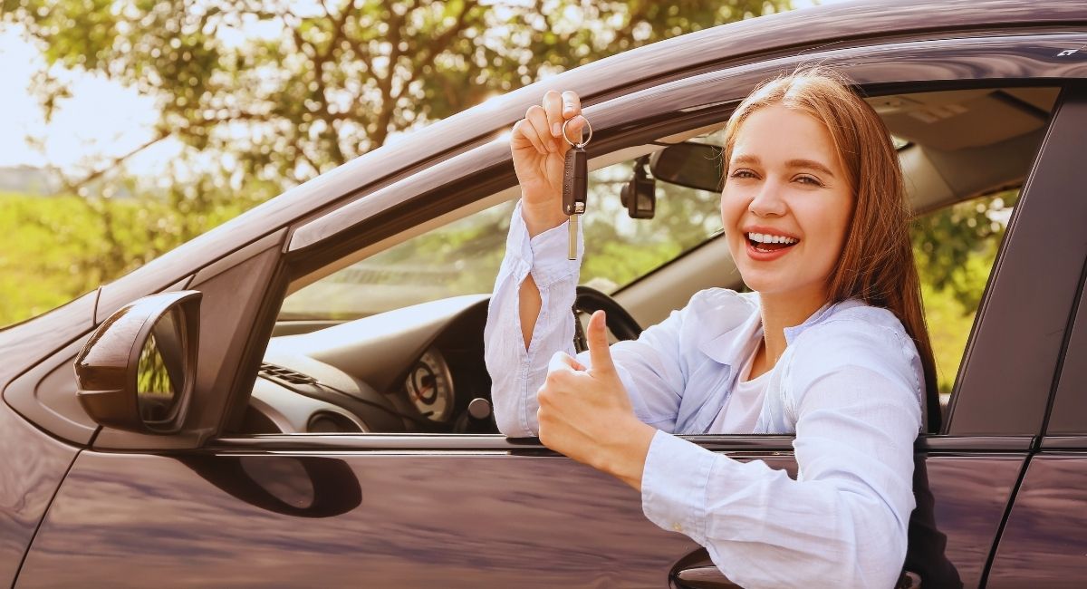 Jeune femme souriante tenant les clés de sa nouvelle voiture