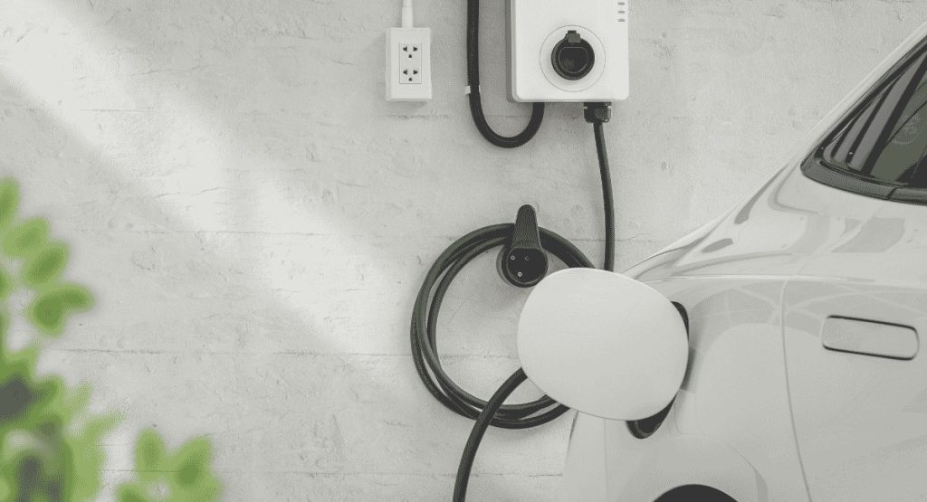 Voiture électrique blanche branchée à une wallbox sur un mur de maison