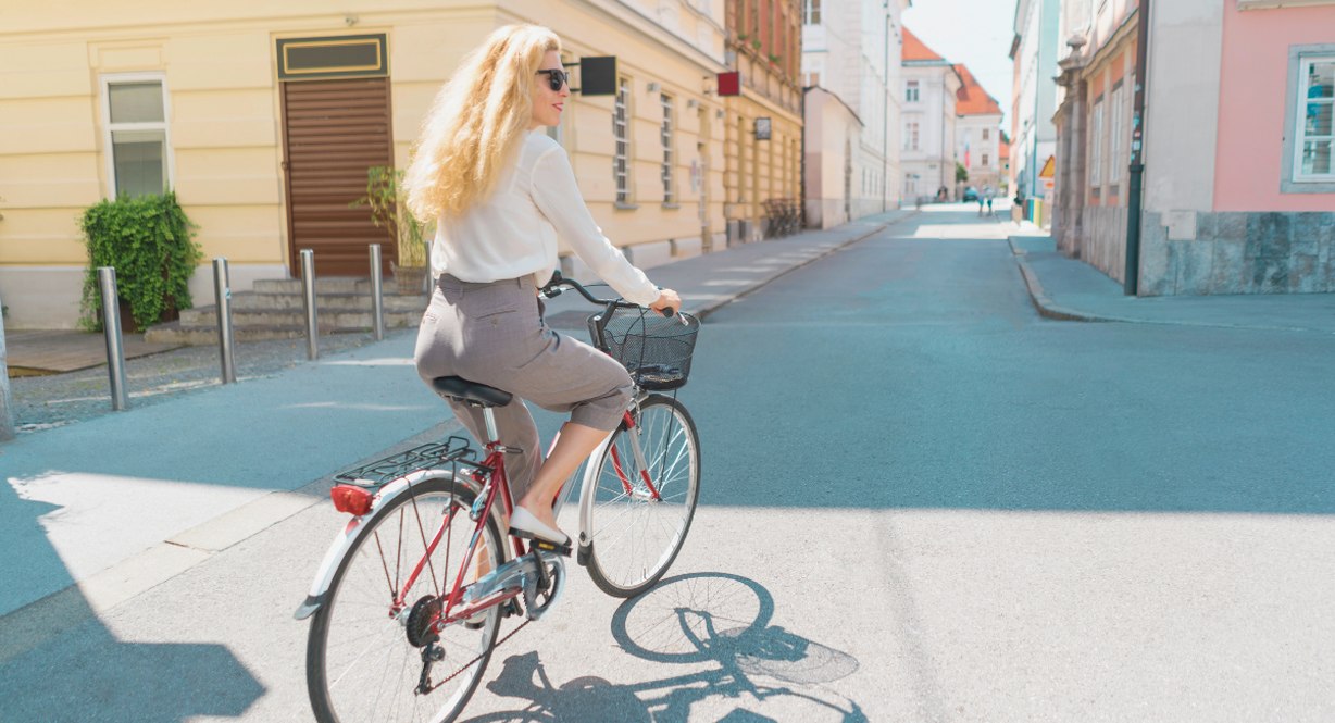 Femme à vélo dans une rue pavée bordée de façades colorées en centre-ville historique