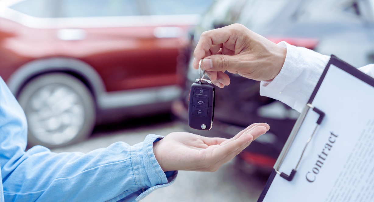 Vendeur remettant les cles d'une voiture d'occasion a un acheteur avec un contrat a la main