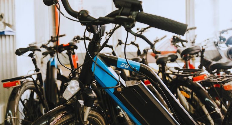 Vélos électriques alignés dans un magasin, batterie intégrée au cadre et étiquettes accrochées
