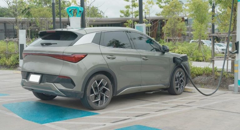 SUV electrique gris branche a une borne de recharge publique sur une place dediee
