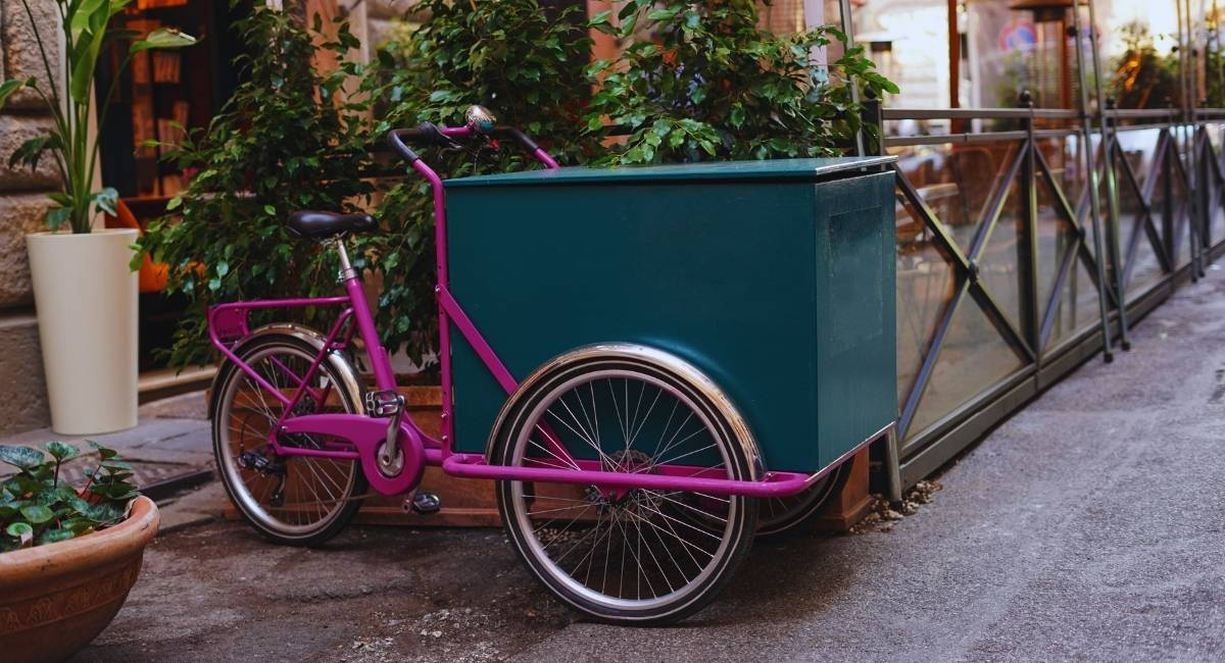 Velo cargo electrique avec caisson de transport stationne le long d une rue commercante