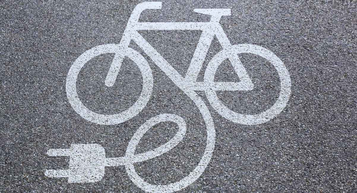 Pictogramme blanc de vélo électrique avec prise peint sur le bitume